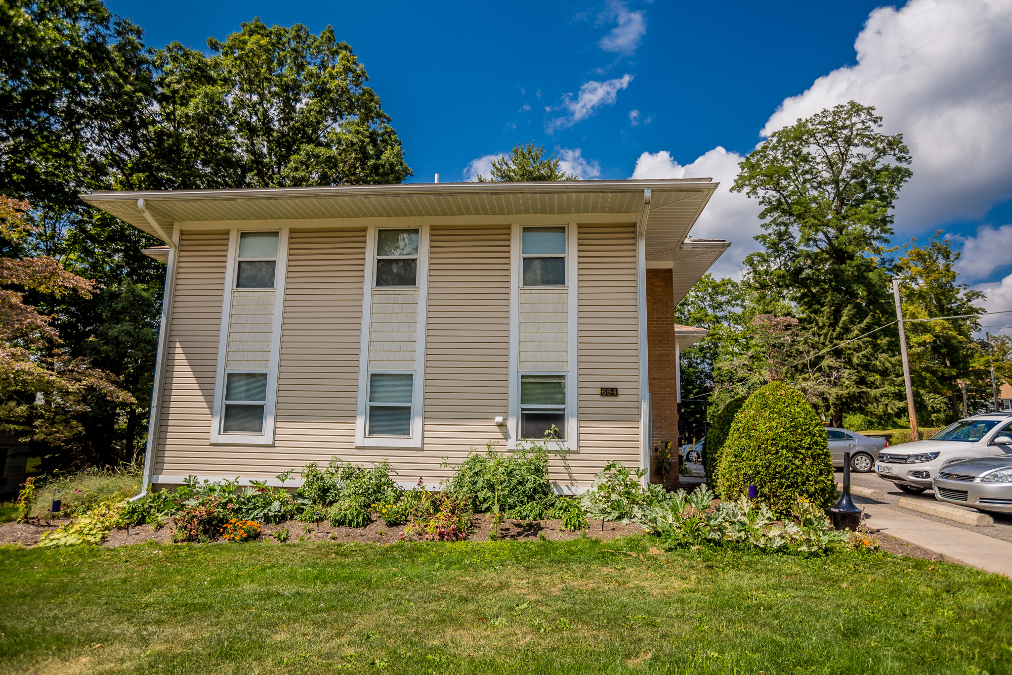 a tan house with a lawn in front of a parking lot